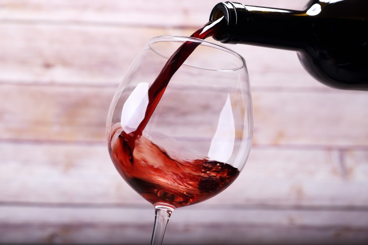 Pouring wine into glass and wooden background