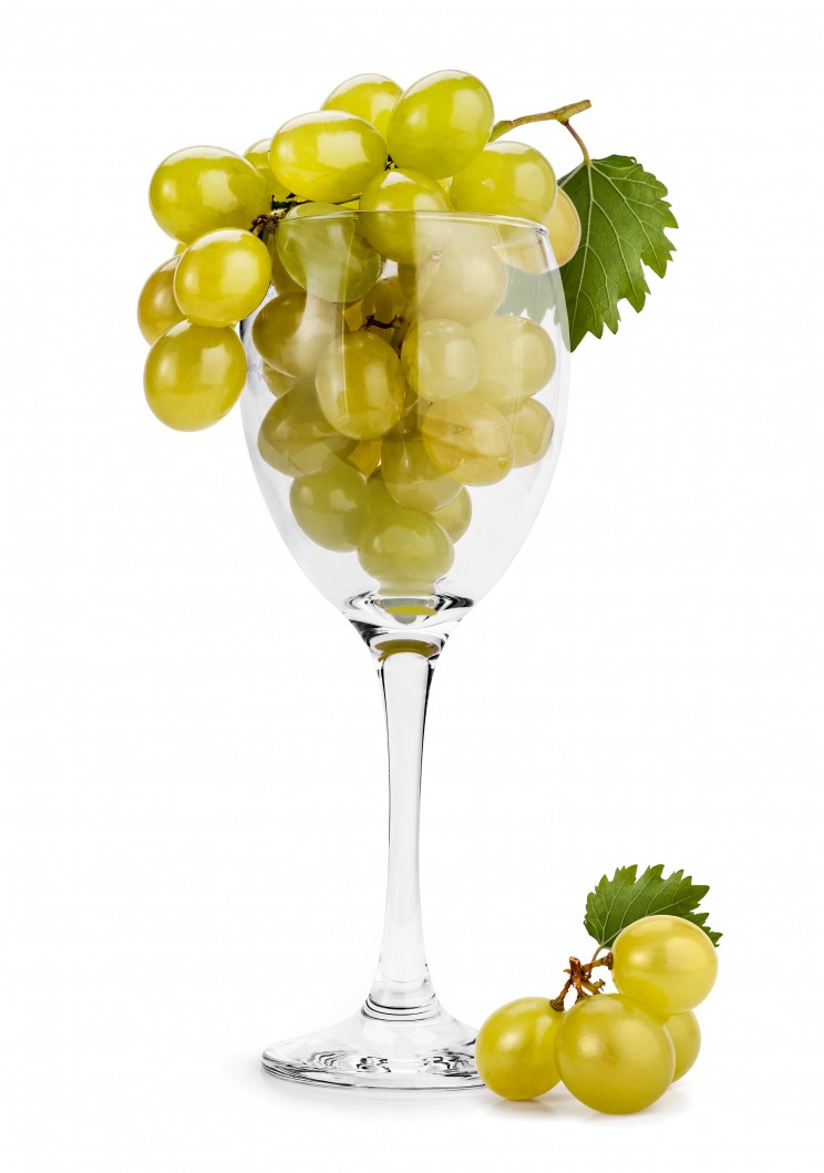 Green grape (Muscat) cluster in a wine glass isolated on white.