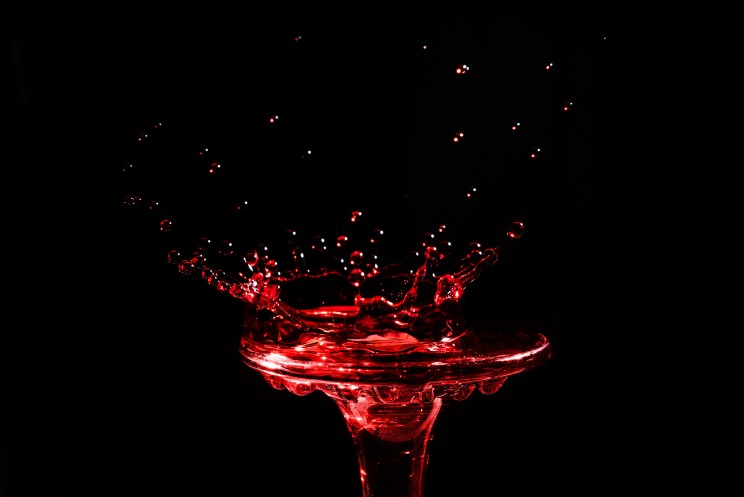 Close-up a drop of wine in the form of a crown is split on the glass  isolated on a black background.