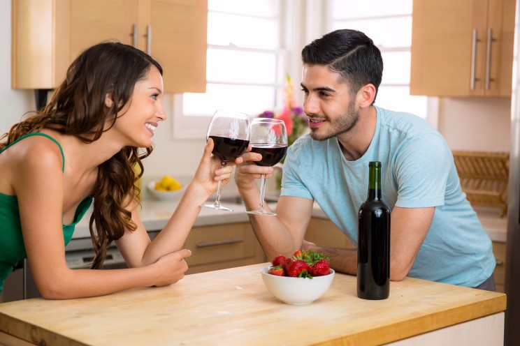 Two lovers stare into each others eyes on a date foreplay with conversation and a romantic mood with wine